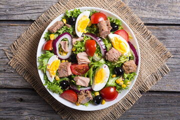 Salat mit Thunfisch, Eisbergsalat, Tomaten, Gurken, Mais, Ei, Zwiebeln und Goudakäse